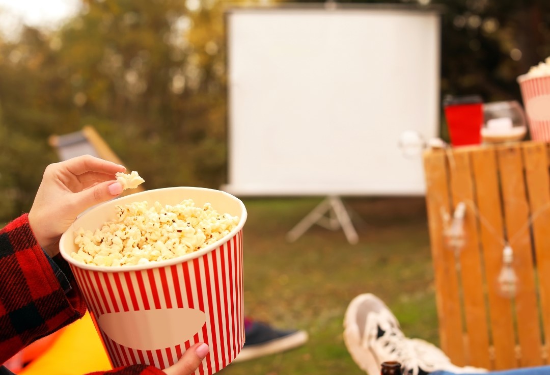 Popcorn-astia ja taustalla valkokangas.